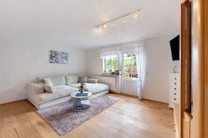 A living room with a sofa, a coffee table, a TV, and a window with curtains.