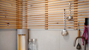 A modern kitchen with wooden slats, a water dispenser, a colander, and a sink. - Holiday Apartment 'Vergissmeinnicht' with Mountain View, Shared Garden and Wi-Fi (Kirchzarten)