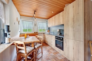 A modern kitchen with wooden cabinets, a dining table with chairs, and a coffee machine.