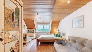 A bedroom with a wooden ceiling, a bed, a sofa, a window, and a painting on the wall. - Sunny Apartment, 85 sqm, 2 Bedrooms, Max. 6 Guests (Kirchzarten)