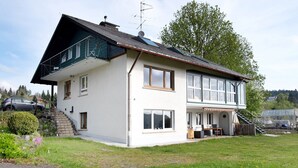Une maison à deux étages avec un balcon, un escalier et un jardin.