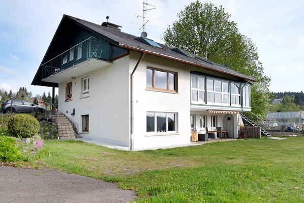 A two-story house with a balcony, a staircase, and a garden.