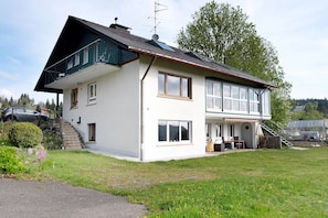 A two-story house with a balcony, a staircase, and a garden.