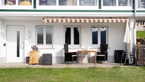 Un bâtiment à deux étages doté d’un patio couvert, d’une porte, de fenêtres et de mobilier d’extérieur.