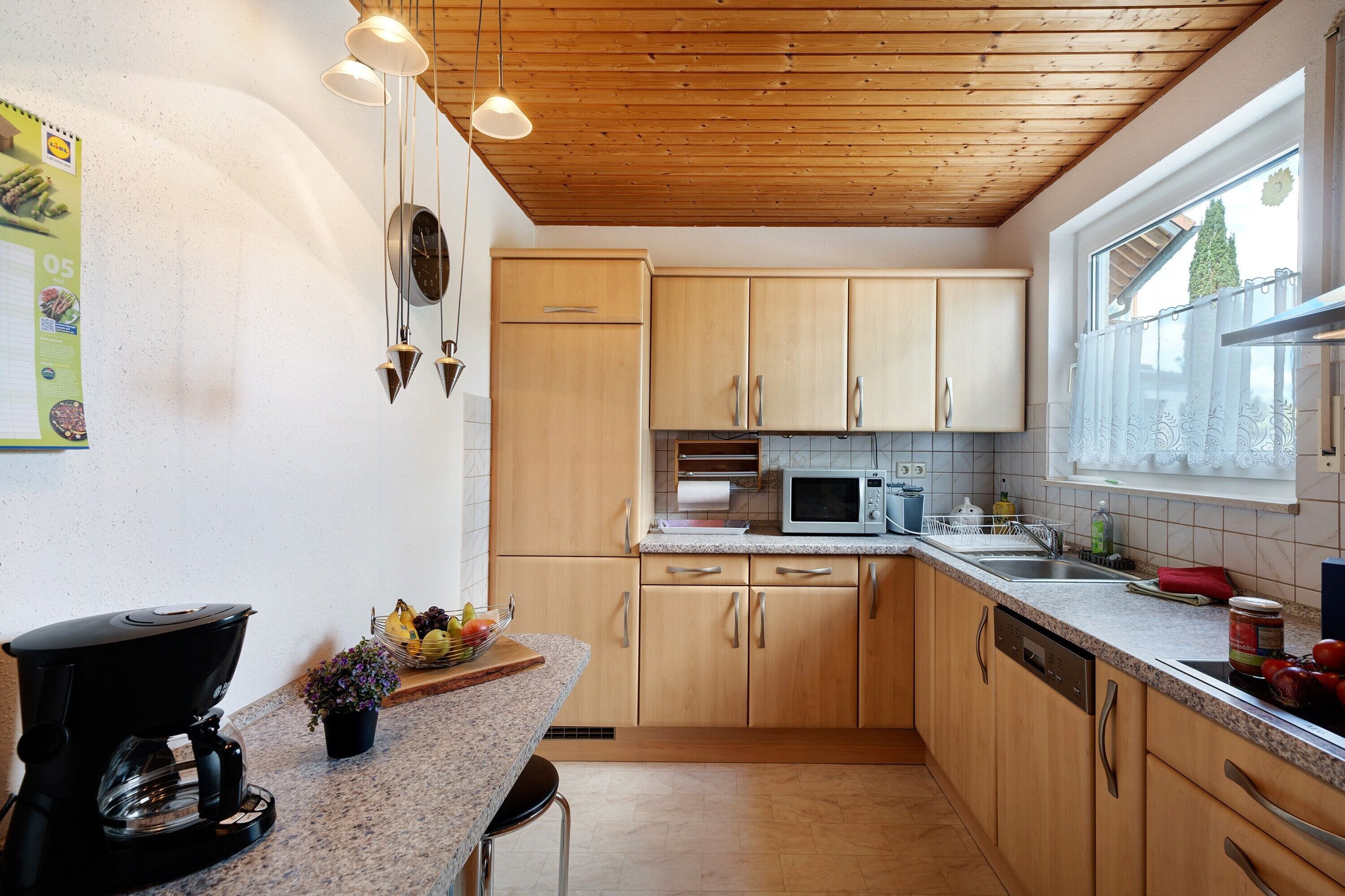 A kitchen with wooden cabinets, a coffee maker, a microwave, and a window with a view.