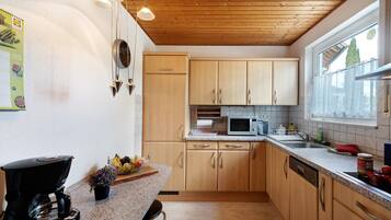 A kitchen with wooden cabinets, a coffee maker, a microwave, and a window with a view.