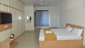 Una camera d'albergo con un letto, una TV, una macchina del caffè e una finestra con tende.