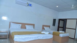 Camera d'albergo con due letti, una testiera in legno, un comodino, un condizionatore d'aria e una porta con uno specchio.