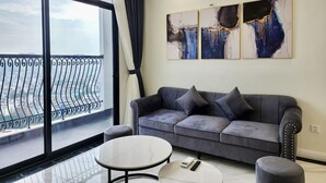 Een moderne woonkamer met een grijze bank, een ronde salontafel en een balkon met een hekwerk.