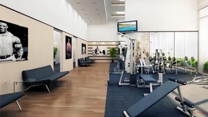 Een moderne sportschool met trainingsapparatuur, een televisie en zitgedeeltes.