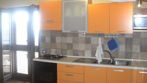 A kitchen with orange cabinets, a stove, and a microwave.