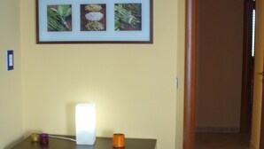 A hallway with a wooden table, a framed picture of plants, and a door leading to another room.