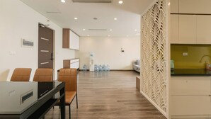 Une chambre d’hôtel avec un plancher en bois, un coin repas avec des chaises, un coin cuisine avec un évier et une cloison décorative.