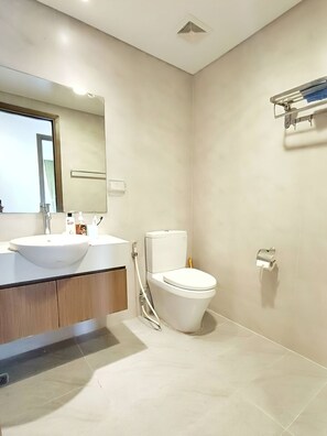 A modern bathroom with a sink, mirror, toilet, and a towel rack on the wall.