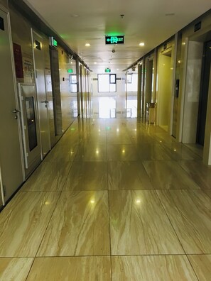 A corridor with a shiny, reflective floor and doors on both sides.