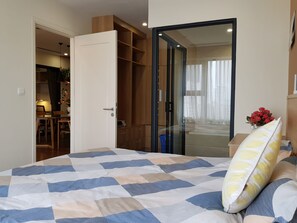 A bedroom with a bed, a wardrobe, a desk, and a window with curtains.