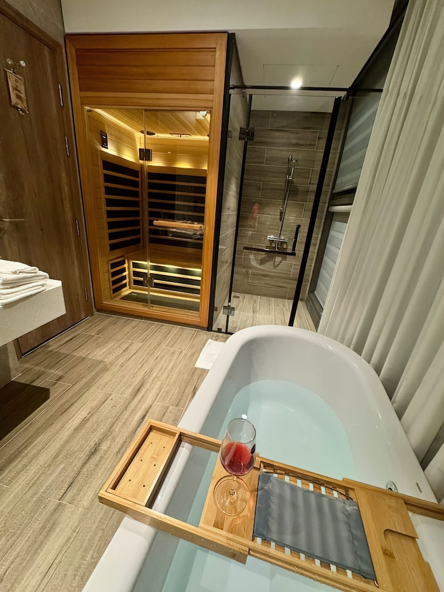 A modern bathroom with a bathtub, a glass shower enclosure, and a wooden vanity with a towel rack.