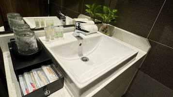 A modern bathroom with a large sink, a mirror, and a small potted plant.