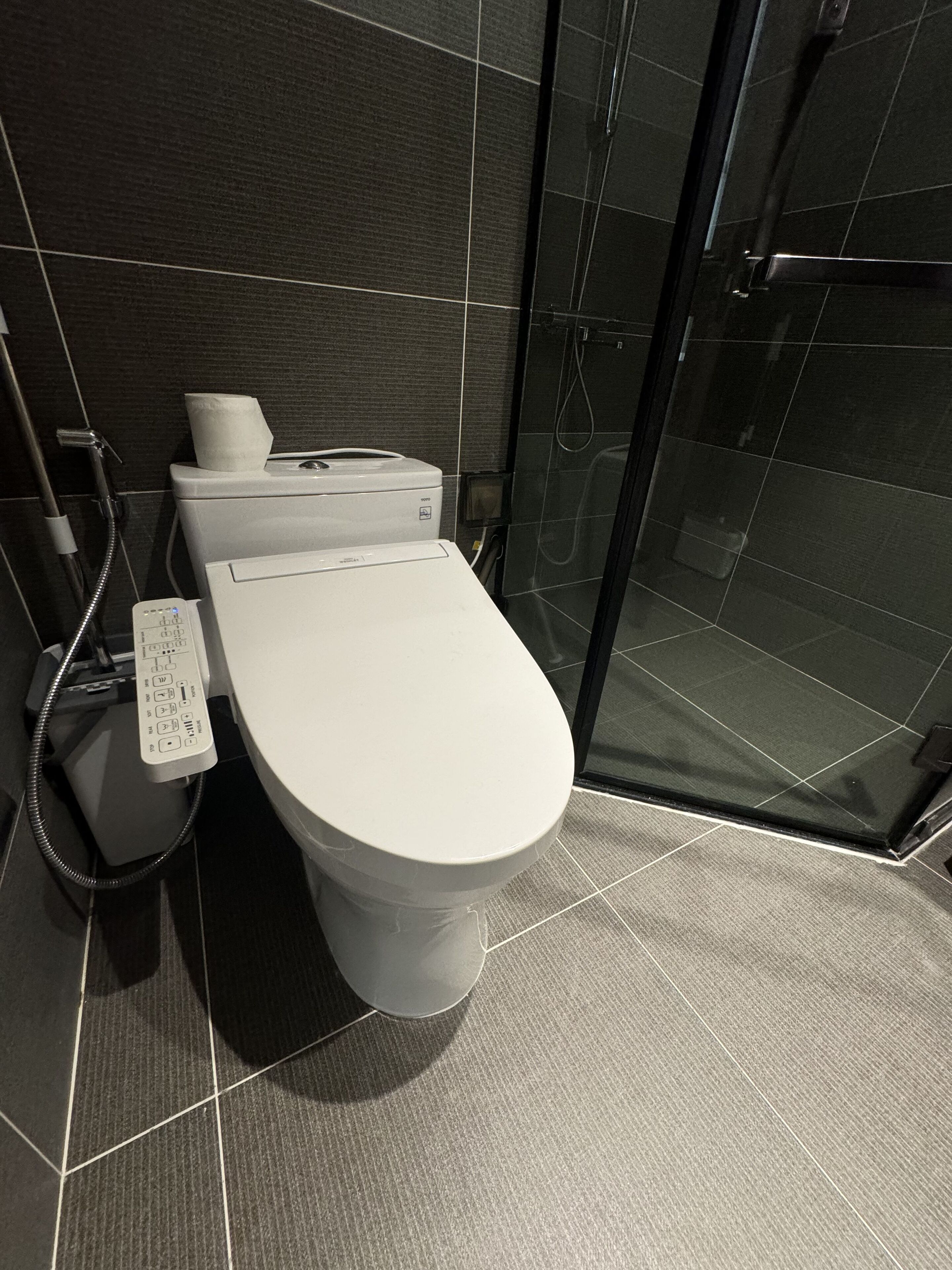 Ein modernes Badezimmer mit Toilette, Papierhandtuchspender und Handbidet.