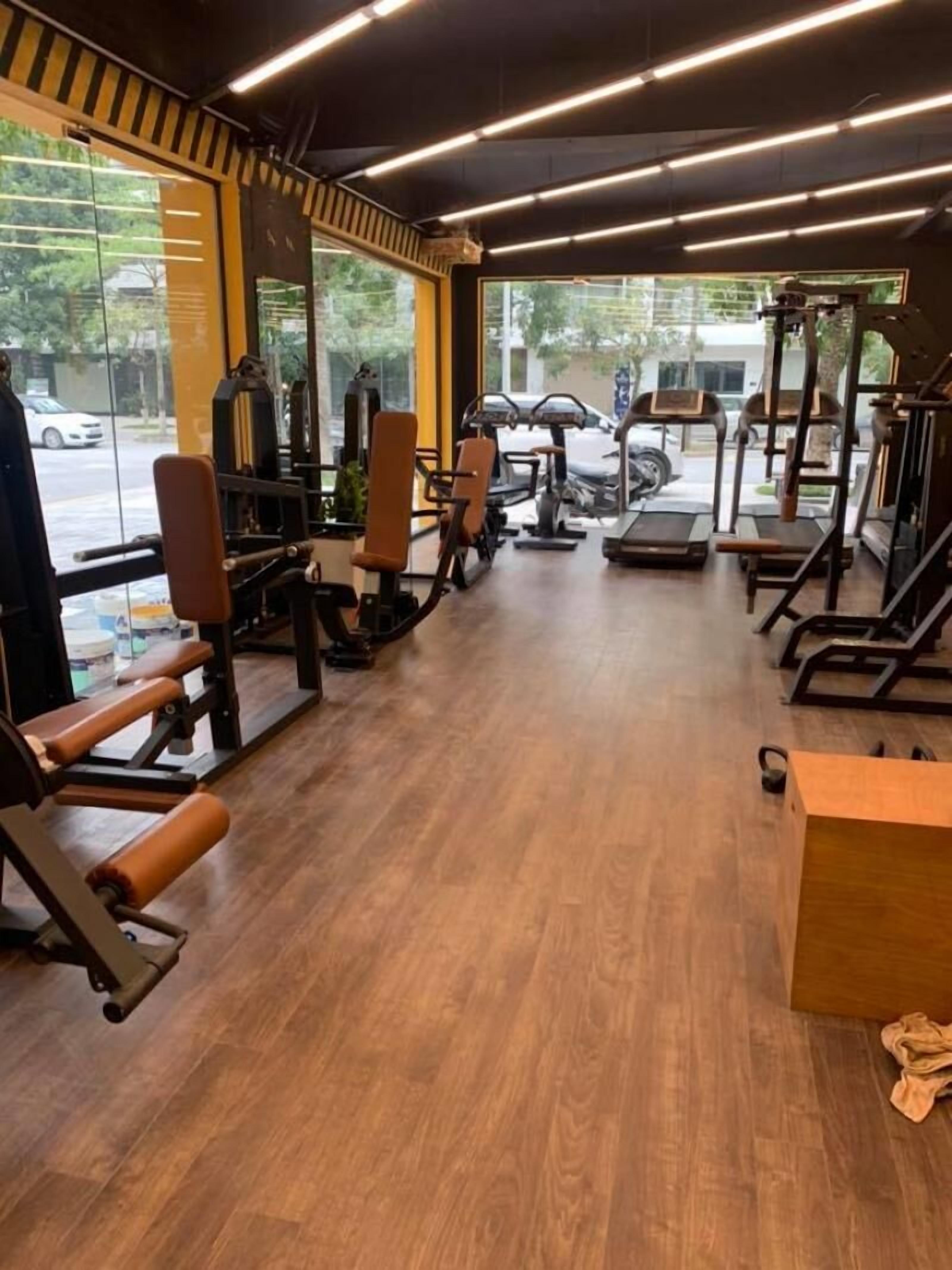 Ein Fitnessstudio mit unterschiedlichen Trainingsgeräten, großen Fenstern und Holzboden.