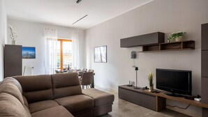 Un salon moderne avec un canapé d’angle, un téléviseur à écran plat et un coin repas comprenant une table et des chaises.