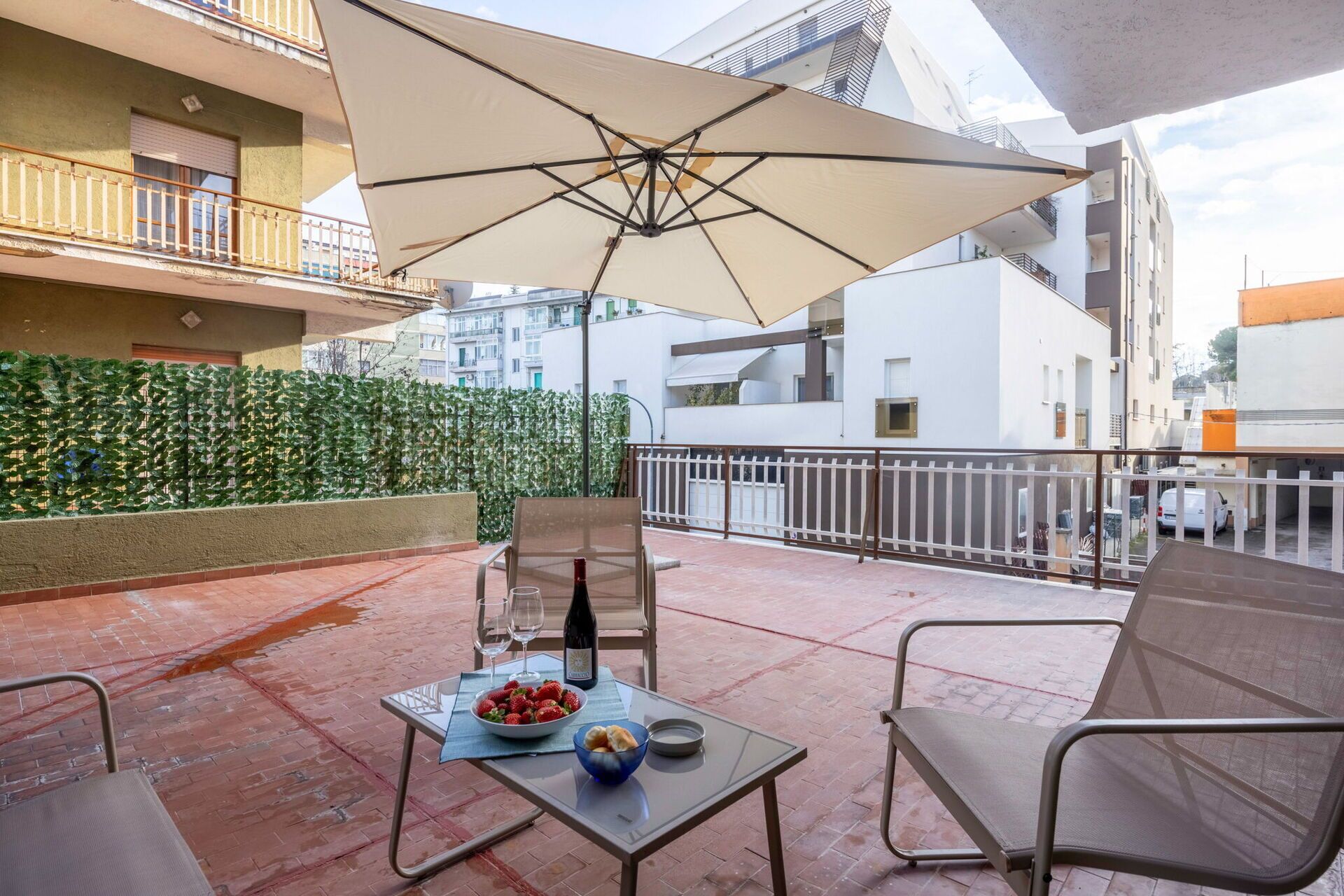 Une terrasse avec une table dressée pour deux, une bouteille de vin et un saladier de fraises.
