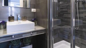 A modern bathroom with a glass shower enclosure, a white sink, and a mirror above it.