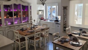 A dining area with a wooden table set for four, white cabinetry, and a purple-lit shelving unit.
