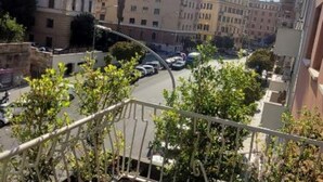A balcony with a view of a street lined with parked cars and buildings.