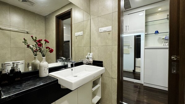 Un bany modern amb un rentapeus blanc, una superfície de lavabo negra i un mirall a sobre. Hi ha dos vasetes amb flors a la superfície.