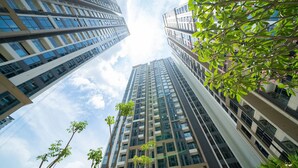 Un immeuble de grande hauteur, doté de nombreux étages et de grandes fenêtres, entouré de verdure et d’autres bâtiments.
