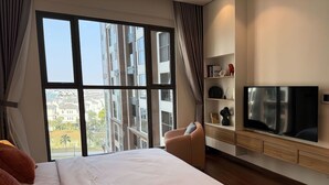 Une chambre d’hôtel moderne dotée d’un grand lit, d’un téléviseur à écran plat et offrant une vue sur la ville grâce à de grandes fenêtres.