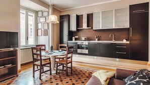 Una cocina moderna con armarios oscuros, un comedor con mesa y sillas, y un piso con diseño.