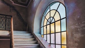 Una escalera con barandilla de madera y un amplio ventanal de arco con diseño de cuadrícula.