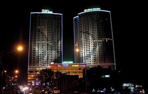 Two high-rise buildings with illuminated signage, likely hotels, featuring a grid-like facade and multiple floors. - Mipec Riverside Long Bien Apartments (Hanoi)