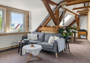 Une pièce chaleureuse avec un canapé gris, une petite table ronde et un bureau en bois.