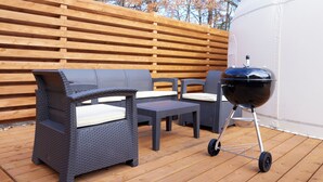 An outdoor patio with wicker furniture, a grill, and a wooden fence. - ReSchool Nasu Glamp (Nasu)