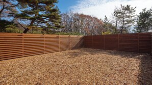 An outdoor area with a wooden fence, gravel ground, and trees in the background. - ReSchool Nasu Glamp (Nasu)