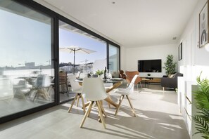 Un espace de vie moderne comprenant un coin repas, un canapé, un téléviseur et une vue sur la ville.