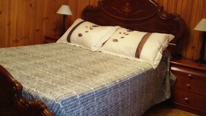 Een slaapkamer met houten lambrisering, een bed, twee nachtkastjes en een spiegel aan de muur.