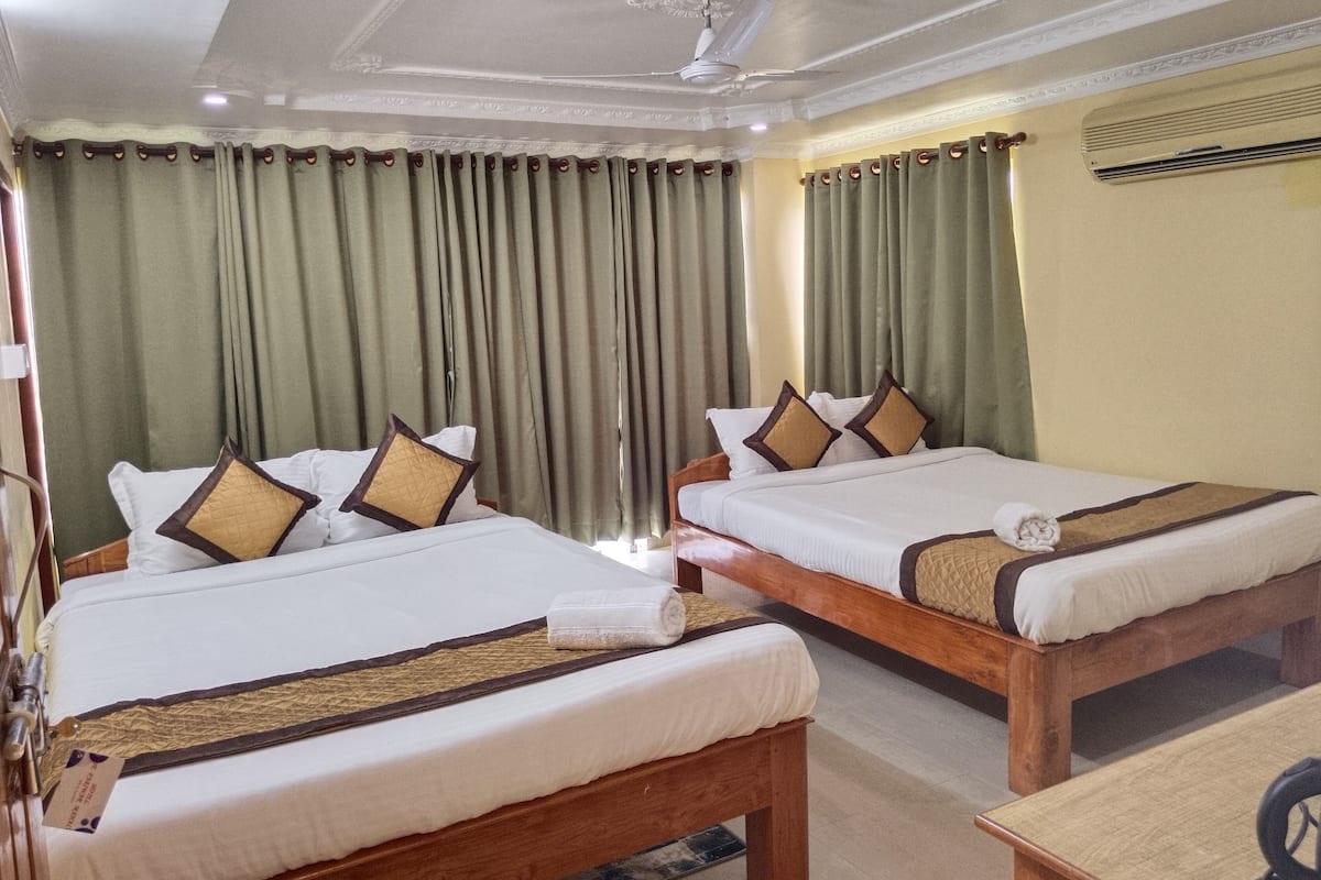 A hotel room with two beds, a wooden headboard, a ceiling fan, and a window with curtains.