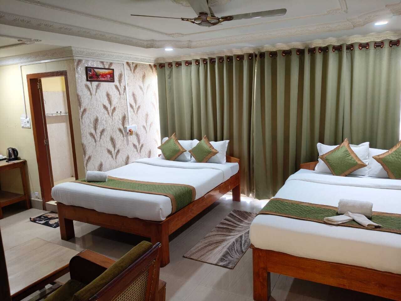 Ein Hotelzimmer mit zwei Betten, einem Deckenventilator, einer Wand mit Muster und einem grünen Vorhang.