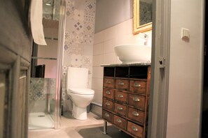 A bathroom with a shower, toilet, and wooden cabinet with drawers. - Authentique et agréable maison (Auch)