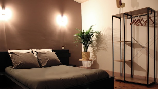 Een slaapkamer met een bed, nachtkastjes, een plant en een kledingkast.