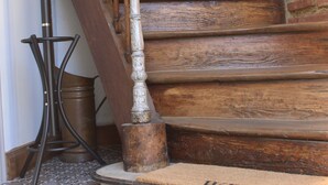 Een houten trap met een metalen leuning, een deurmat met de tekst 'WELCOME' erop, en vloertegels met een patroon.