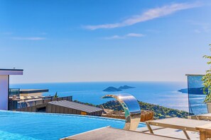 A modern infinity pool with a clear view of the ocean and islands in the distance.
