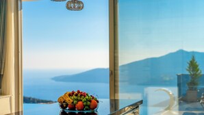 Un cuenco de fruta en un balcón con vistas a las montañas y al mar.
