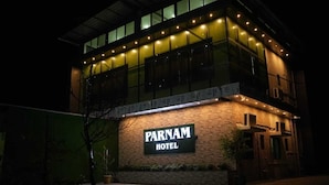 Un edificio con un letrero que dice 'PARNAM HOTEL' de noche.