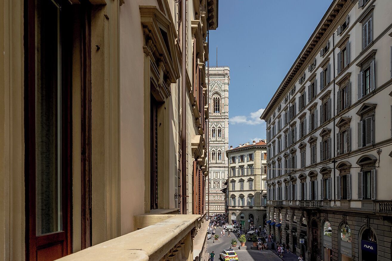 Une vue de rue avec des bâtiments historiques, une tour imposante et une zone piétonne animée.