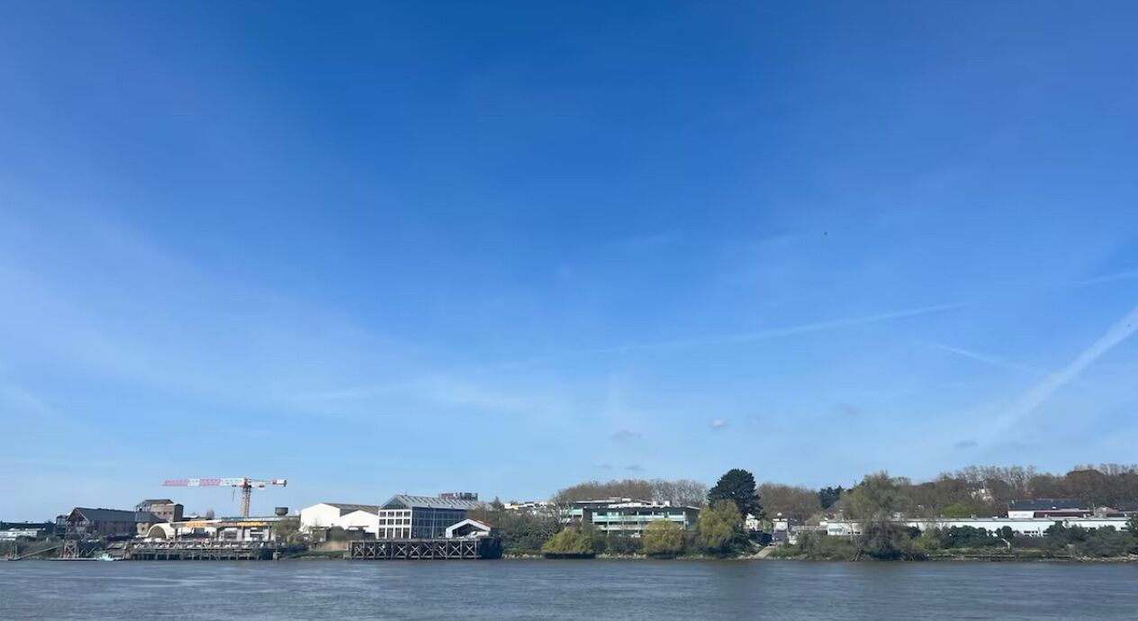 A waterfront view with buildings, a dock, and a crane.